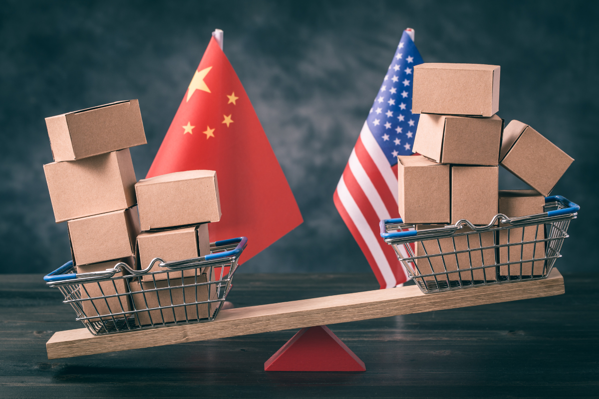 Filled shopping basket and cart with US and Chinese flags on the seesaw, which reflects the trade balance concept.