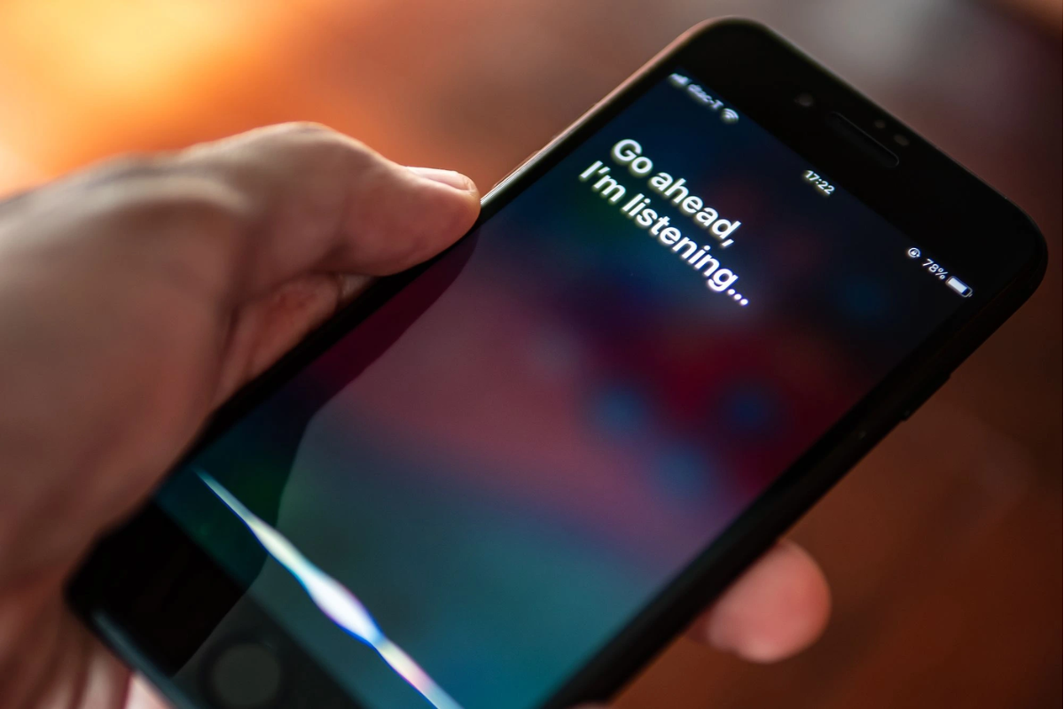 The image shows a mobile phone with the inscription "Go ahead, I'm listening", which indicates the use of AI assistants.