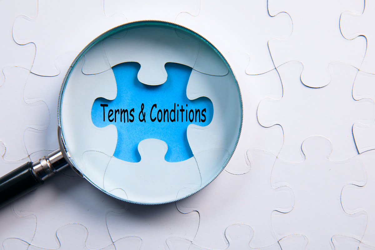 The image shows a magnifying glass pointing to the "Terms and Conditions" sign.