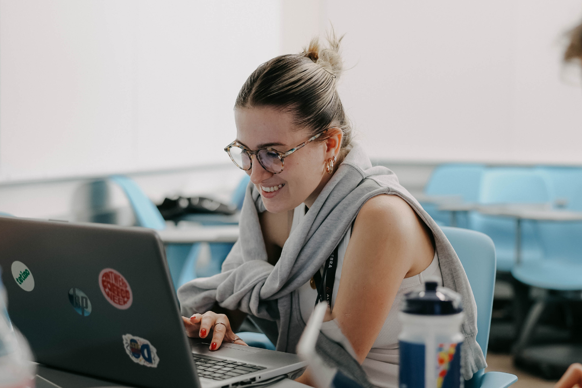 The picture shows a woman sitting in front of a laptop and laughing.