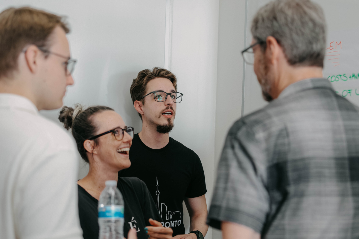 The image shows several ABC Silicon Valley 2024 participants discussing an assignment with the professor.