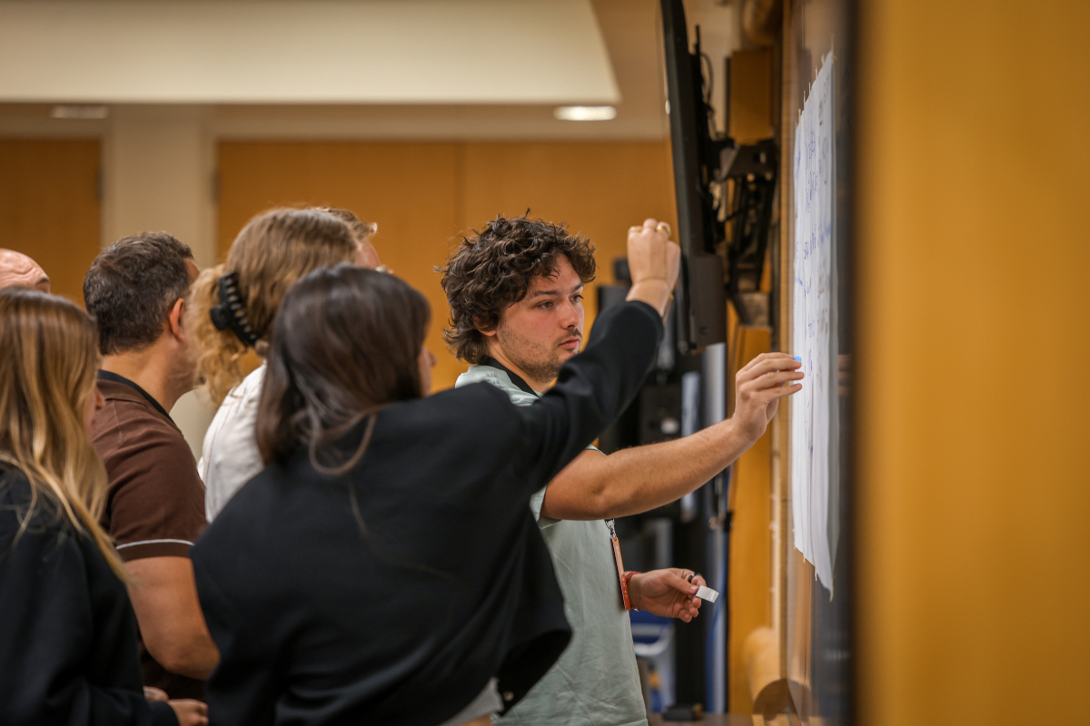 The image shows several ABC Silicon Valley 2025 participants sticking post-it notes to the whiteboard.