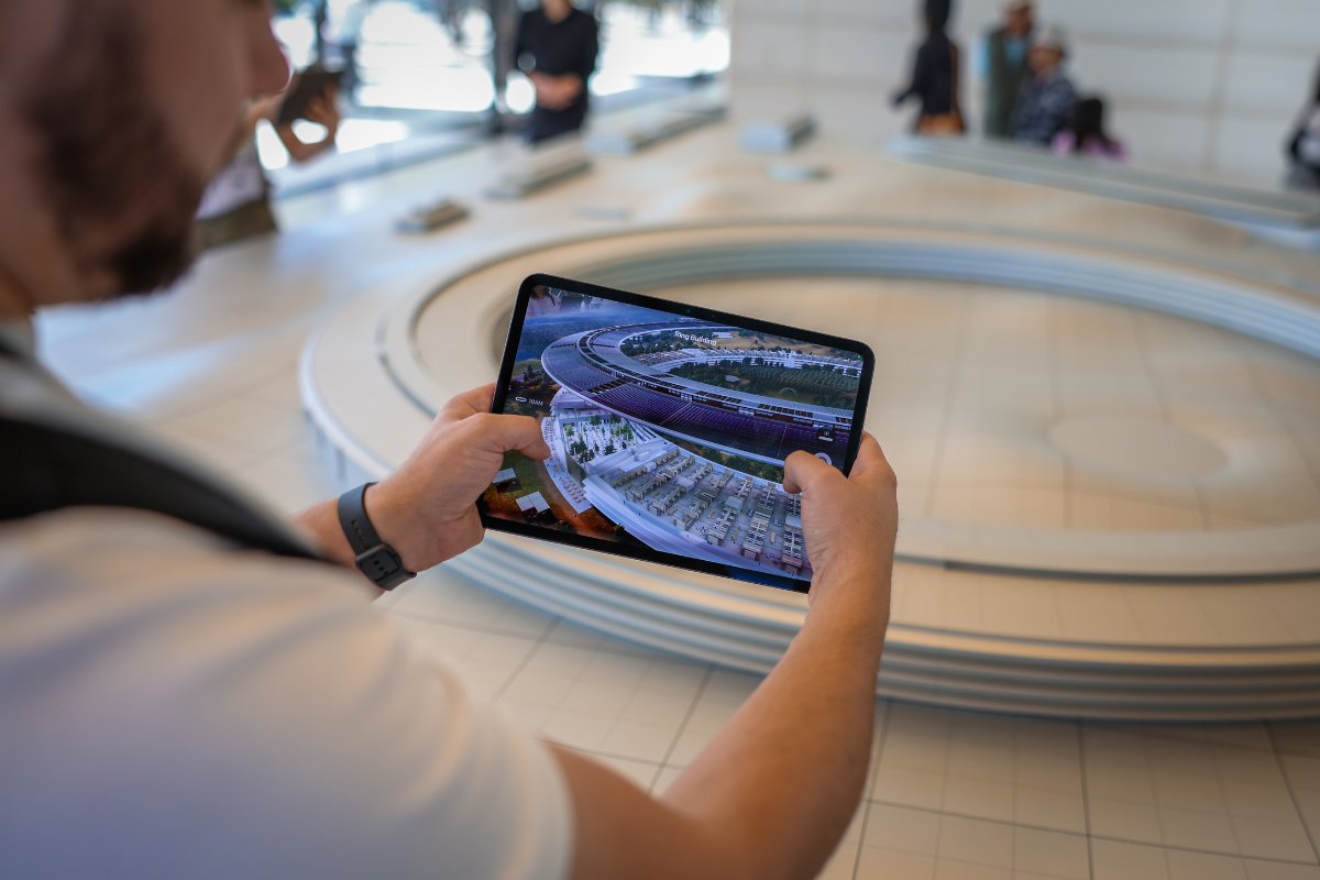 The image shows a tablet using smart technology to recognize a building model in front of it, displaying on the screen what the interior of the building looks like.